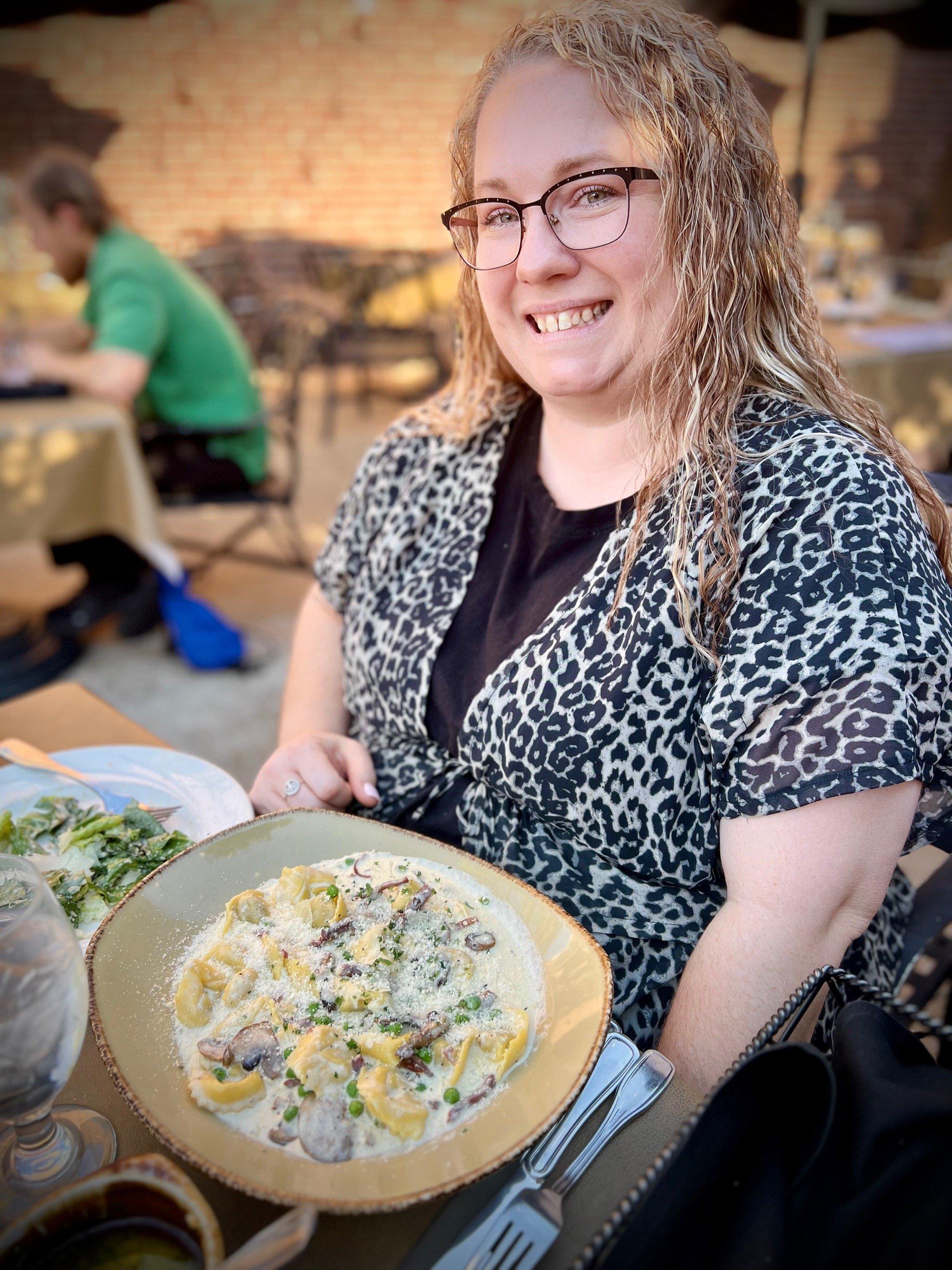 a woman smiling and sitting at a table with food