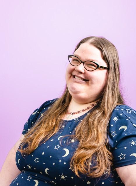 a woman with long hair and glasses smiling