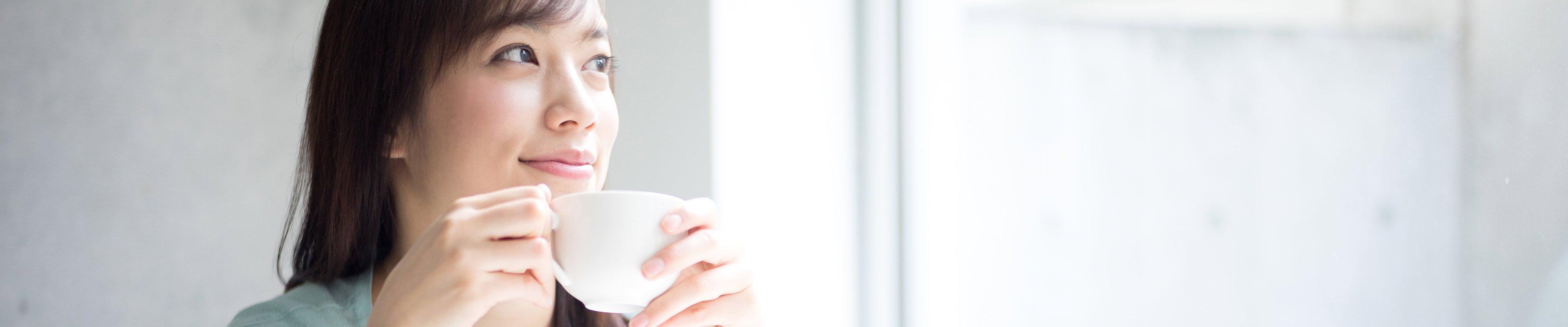 Woman holding cup of tea think about growth mindset.