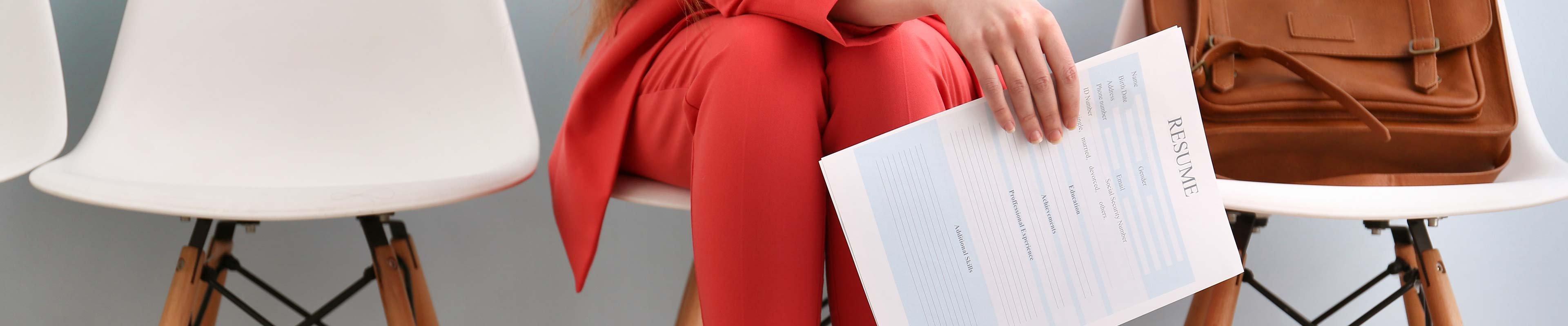 A woman dressed professionally sitting while holding a resume